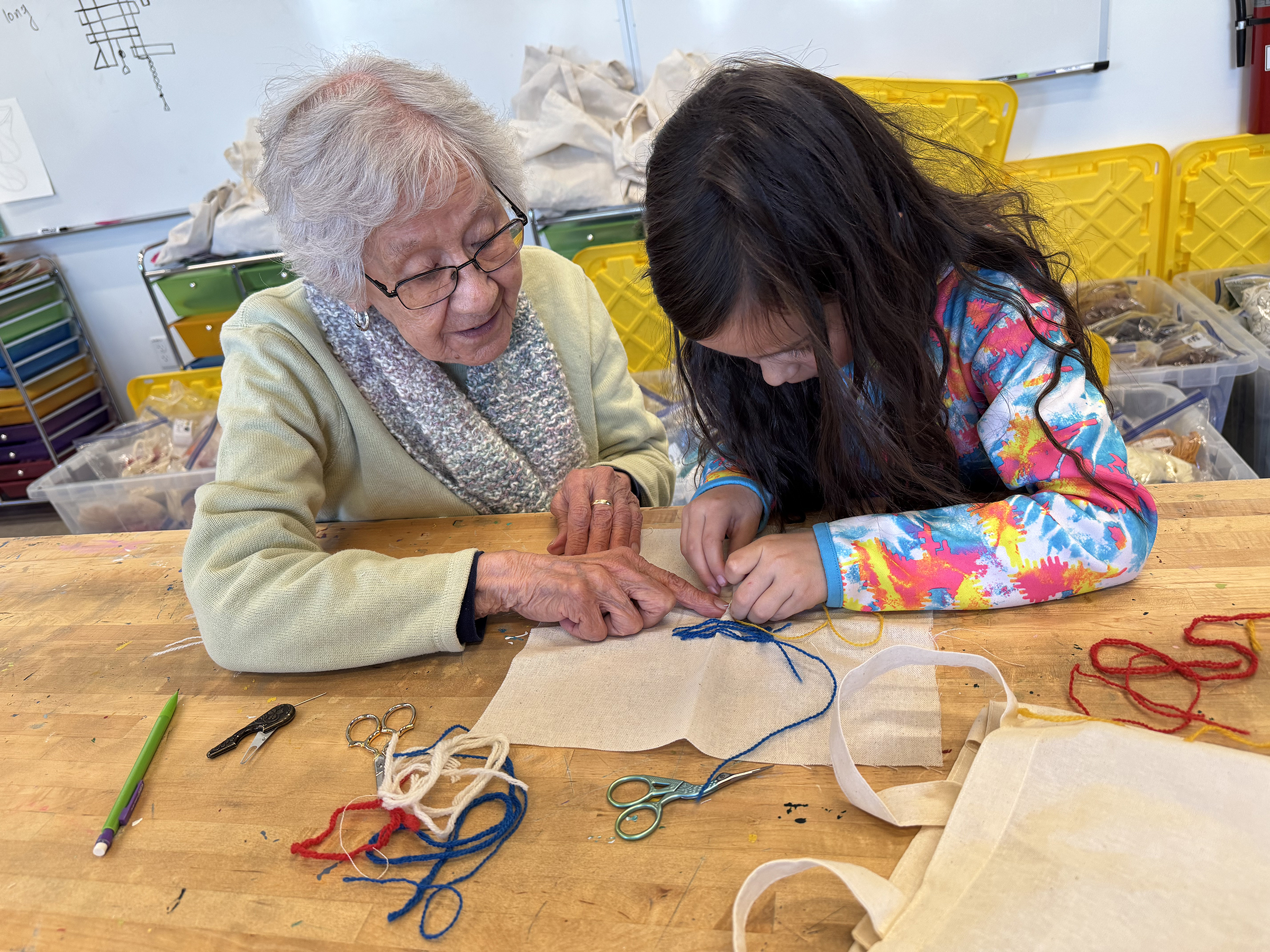Artist Patsy Garcia shares the traditional colcha stitch with a Mountain Valley School 1st grade student